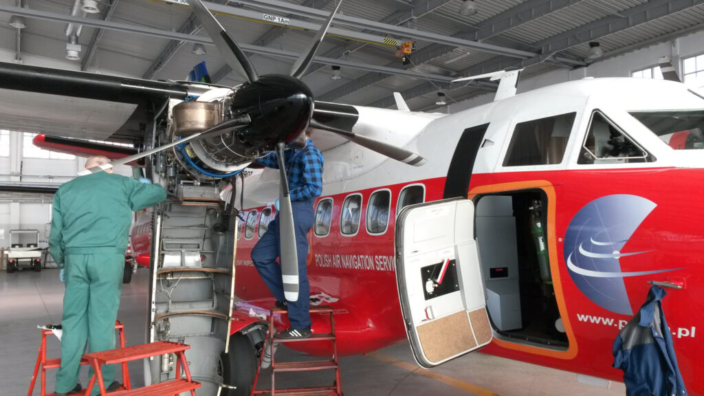 Mechanicy lotniczy podczas przeglądu silnika samolotu L-410 w hangarze na Lotnisku Chopina w Warszawie (5 listopada 2014 r.). Zdjęcie: Paweł Witeska